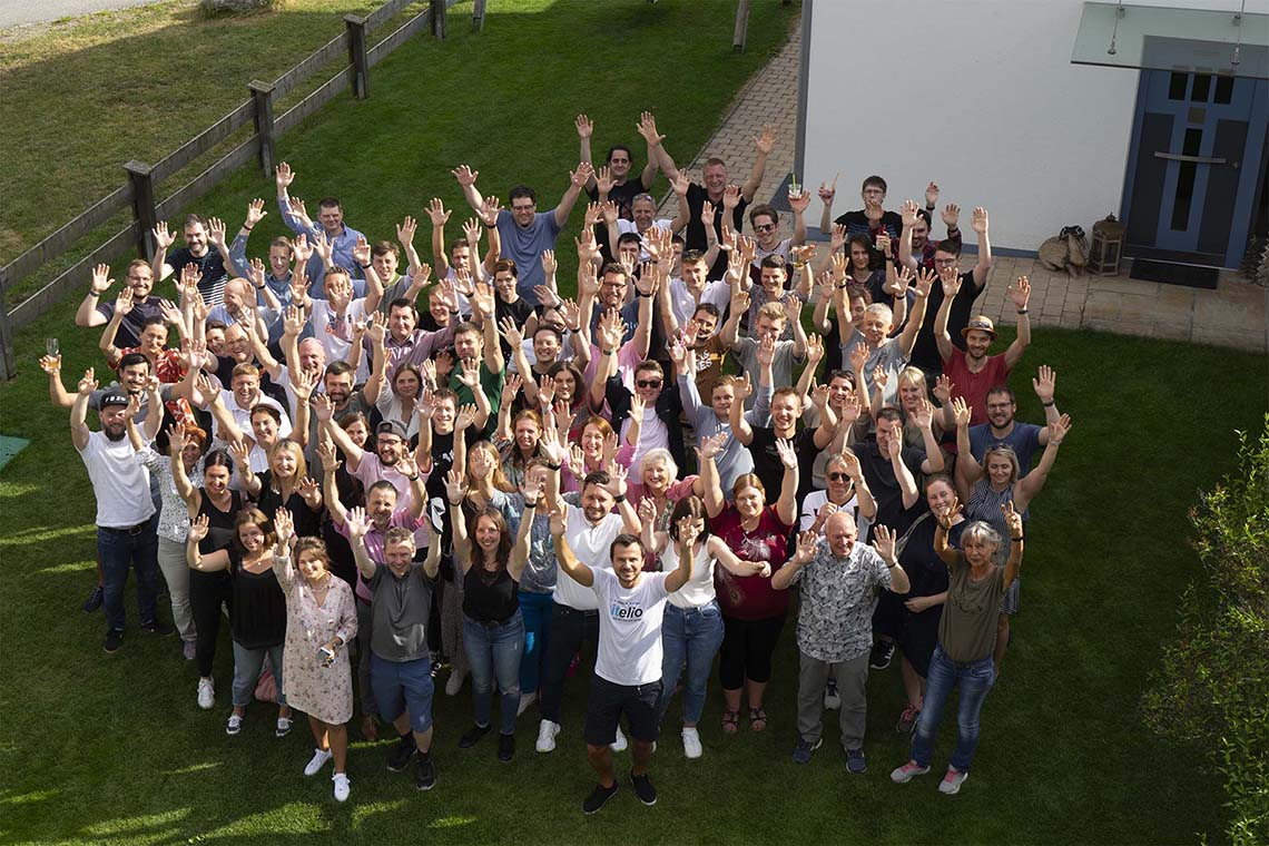 Gruppenfoto der Mitarbeiter von itelio im Garten der Firmenzentrale in Kiefersfelden, aufgenommen beim itelio Familienfest 2023.
