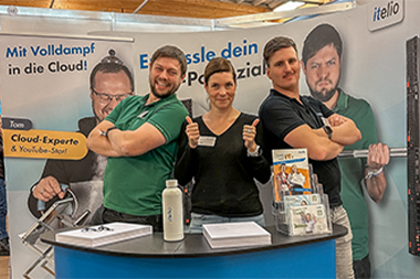 Julia Doetsch mit zwei Mitarbeitern am Stand der itelio GmbH bei einer Karrieremesse.